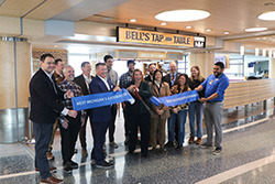 Airport officials and staff holding a ribbon reading "West Michigan's Gateway" near Bell's Tap and Table