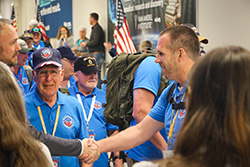 A man shaking hands with a veteran at an Honor Flight welcome event