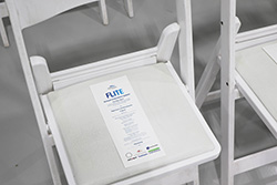 Close-up of a folding chair with a FLITE branded program placed on the seat