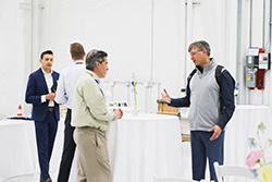 Three attendees in business attire talking near a reception table at an event