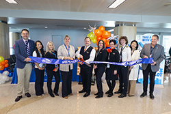 Airport staff at a ribbon-cutting ceremony with orange and blue balloons