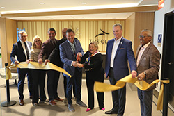 Ribbon-cutting ceremony for "The Club" lounge with a group holding a gold ribbon