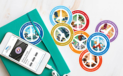 Colorful destination-themed circular sticker collection displayed with a notebook and phone