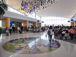 Wide view of a busy airport terminal concourse with hanging ceiling decor