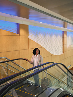 Woman riding an escalator inside the terminal with luggage