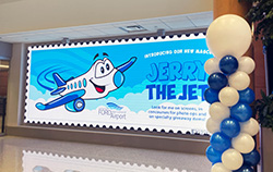 Terminal video wall banner introducing the Jerry the Jet mascot, flanked by balloon decor