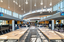Interior view of an airport lounge with hanging light fixtures at dusk