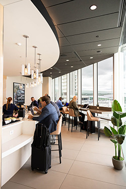 Travelers seated at a lounge counter with a city skyline view