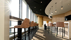 Interior of a rooftop-style lounge with tall windows and bar stools